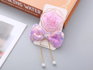 Detail von rosa Netzblumen-Clip und lila Pailletten-Schleife auf handgemachter Karte