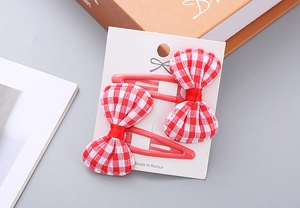 Close-up of red plaid bow hair clips for girls on a white display card set of two