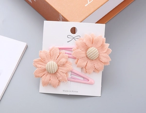 Detailed close-up of pink daisy floral hair clips with fabric petals and striped center