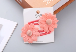 Detail of pink daisy fabric hair clips for girls on display card with bow accents