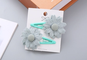 Detail of two-piece grey-blue fabric flower hair clips with blue striped buttons
