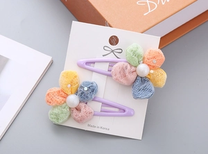Detail of two colorful mesh flower hair clips on a purple metal base with pearl centers