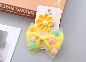 Detail von gelber Blumenklammer mit Perle und Netzschleifenclip mit bunten Bommeln