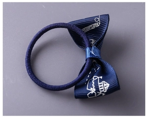 Detailed close-up of a navy blue floral bow hair tie with white castle patterns