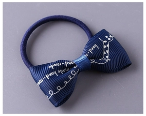 Detail of dark blue handmade bow hair tie with giraffe pattern and ribbon texture