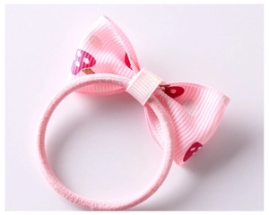 Close-up of pink ribbon bow hair tie for girls featuring cute strawberry patterns
