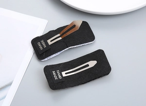 Detailed view of handmade black felt BB hair clips with signature hand made label