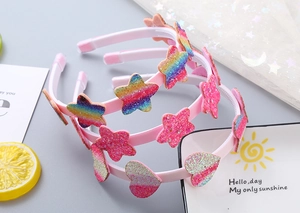 Dettaglio di cerchietti rosa per bambini con cuori e stelle glitterate arcobaleno