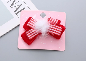 Dettaglio del fermaglio per capelli in velluto rosso per Capodanno con pompon bianco