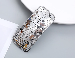 Detail shot of silver sequined rectangular hair clip on a minimalist grey surface