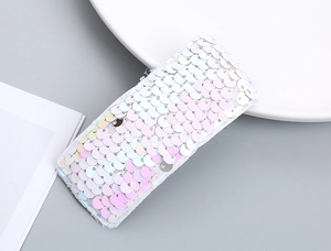 Detailed close-up of a rectangular hair clip featuring iridescent white sequins and fine stitching