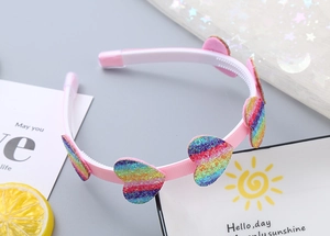 Dettaglio del cerchietto rosa per bambini con cuori arcobaleno glitterati e denti antiscivolo