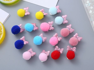 Close-up of children's glitter bows and soft plush ball hair clips in vibrant candy colors