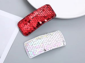 Close-up of sparkling sequin hair clips in red and pearl white with hand-stitched edges