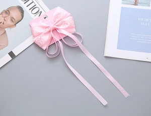 Dettaglio del fermaglio per capelli a fiocco rosa con nastro a fiori su cartoncino