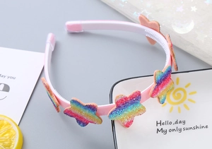 Dettaglio di stelle glitterate e cuori rosa su un cerchietto arcobaleno per bambine