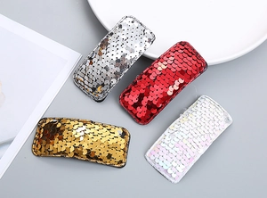 Detailed view of four colorful sequin snap hair clips in silver red gold and white