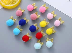 Flat lay detail of colorful plush pom pom bow ear clips for girls in various bright colors