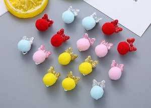 Detail view of colorful pompom bow ear clips for kids in red pink yellow and blue