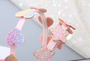 Dettaglio macro del cerchietto per bambini con cuore e stella glitter e nastro rosa