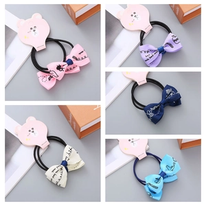 Close-up of 5-piece handmade floral bow hair ties in assorted pastel colors on bear card