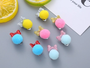 Detail of 8pcs glitter bow and colorful pompom ear clips set for kids on grey background