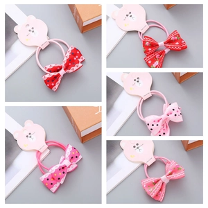 Detail of five handmade floral bow hair ties on pink bear-shaped display cards
