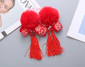 Dettaglio del fermaglio rosso per Capodanno Cinese con pompon di peluche e nappa lunga