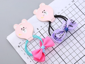 Detail of handmade bow hair ties with printed ribbon and elastic bands on a scale card