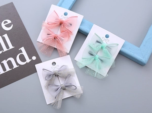 Detailed view of kids' mesh bow hair clips in pastel pink, mint green and soft grey