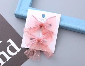 Detailed view of pink mesh bow hair clips with gold sequins on display card