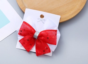 Dettaglio del fiocco per capelli fatto a mano rosso e bianco con paillettes