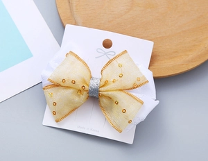 Dettaglio del fiocco per capelli per bambine con pizzo, paillettes oro e centro glitter