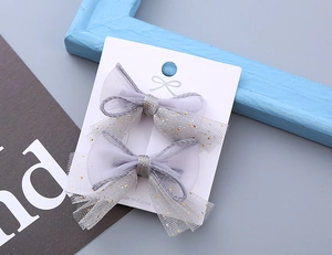 Detail of gray mesh hair clips with gold glitter for kids on a white display card