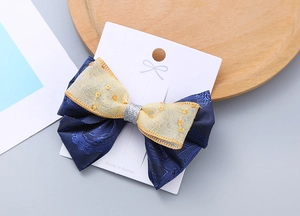 Dettaglio di un fiocco per capelli blu e giallo con paillettes su cartoncino