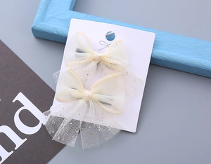 Detail of sweet tulle bow hair clips with gold glitter on white display card