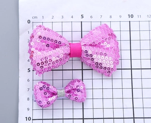 Größenvergleich von zwei rosa Pailletten-Haarschleifen an einem Zentimeter-Lineal