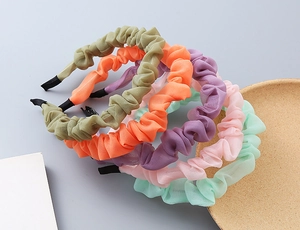 Dettaglio di cinque cerchietti in chiffon plissettato in colori pastello per ragazze