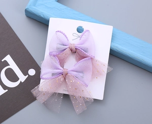 Detail of purple tulle bow hair clips with gold glitter on white display card