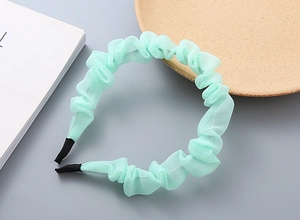 Dettaglio ravvicinato del cerchietto in chiffon verde menta pieghettato con punte nere