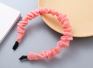 Dettaglio del cerchietto in chiffon plissettato rosa con trama morbida e punte antiscivolo