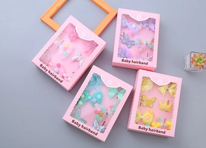 Detail of four baby hair accessory gift sets with bows, crowns and colorful pom-poms