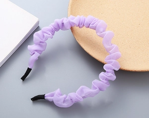 Dettaglio macro del cerchietto a pieghe viola in chiffon con trama a strati e punte antiscivolo nere