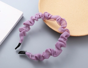 Dettaglio del cerchietto in chiffon plissettato viola con bordi a balze e punte morbide