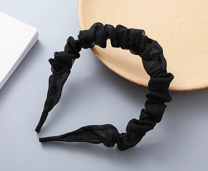 Dettaglio del cerchietto nero con pieghe che mostra la trama fine del tessuto chiffon
