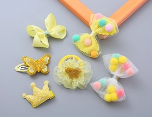 Close-up of yellow children's hair accessory set with lace bows and sparkly crown clips