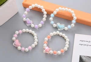 Detail of four handmade beaded bracelets featuring white pearls and colorful heart charms