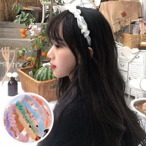 Dettaglio del cerchietto in organza increspata bianca con campioni di tessuti colorati