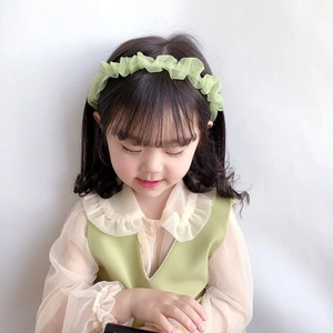 Primo piano di un cerchietto in chiffon plissettato verde menta indossato da una ragazza