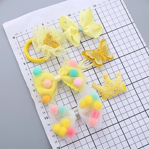 5-piece yellow kids hair accessory set with satin bows and sequin crown on a grid board